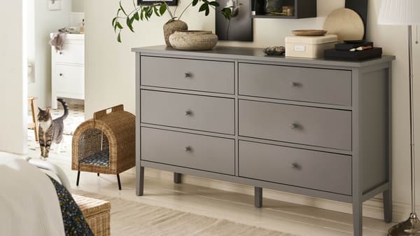 A 6-drawer GULLABERG gray dresser in a bedroom with decor on top of it.