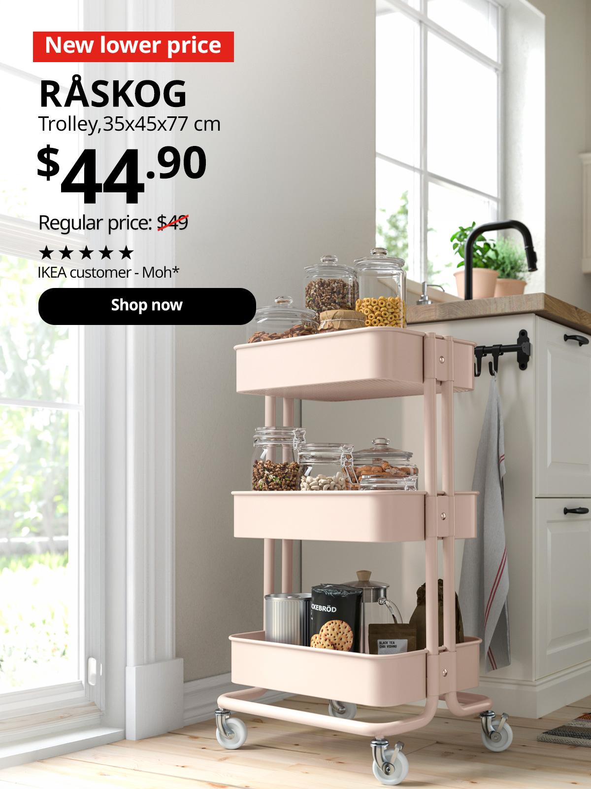 A angled shot of a pink RÅSKOG trolley in the kitchen next to the kitchen sink and door to the backyard. In the top left corner, a red tag with white text reads 'New lower price'. Accompanying black text displays: 'RÅSKOG, Trolley, 35x45x77 cm, $44.90, Regular price: $49'