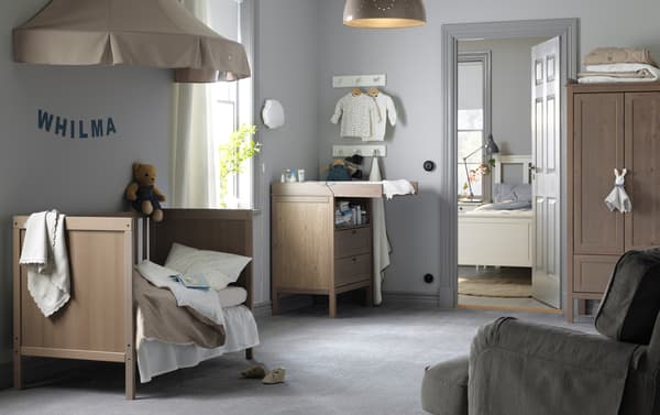 A baby's room with light brown furniture. 