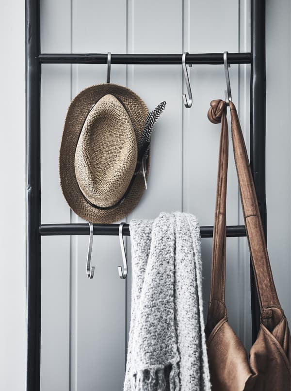 A bag, a hat and a throw hanging on hooks on a ladder.