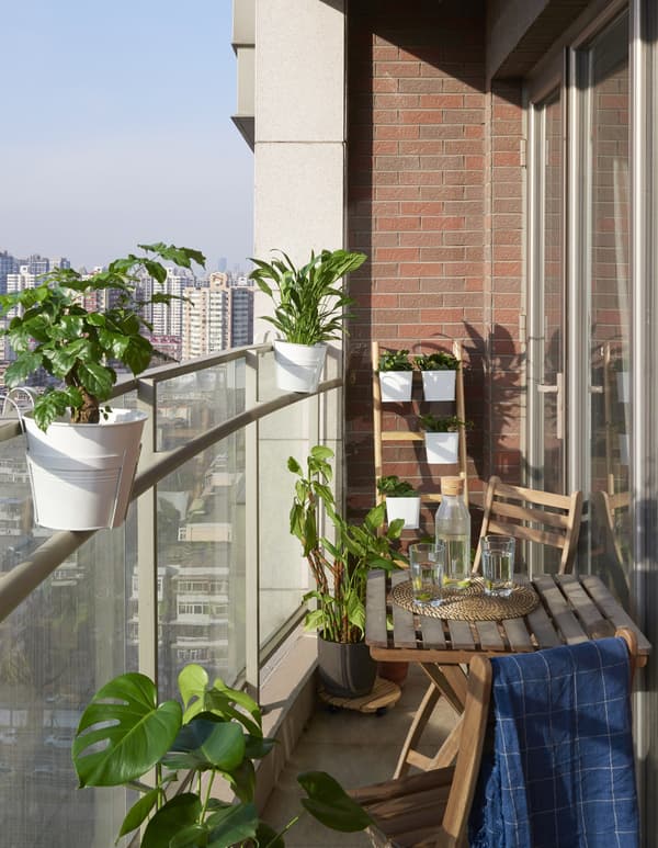 A balcony with plants and a table and chairs.