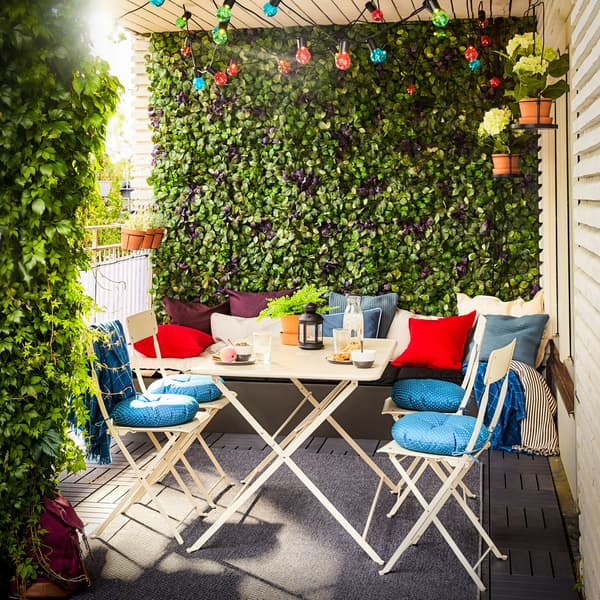 A balcony with SALTHOLMEN table and four chairs in beige with bright blue cushioned seats.