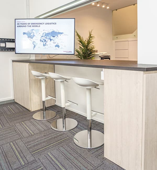 A bar area showcasing a dark grey countertop with bar stools tucked in.