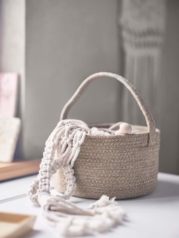A basket with knitted rope coming out of it.