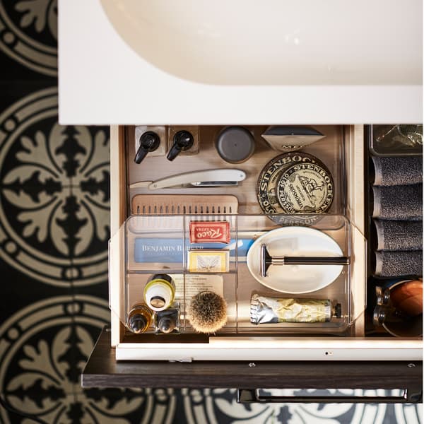 A bathroom drawer is open to show organised bathroom storage inside smoked organising boxes.