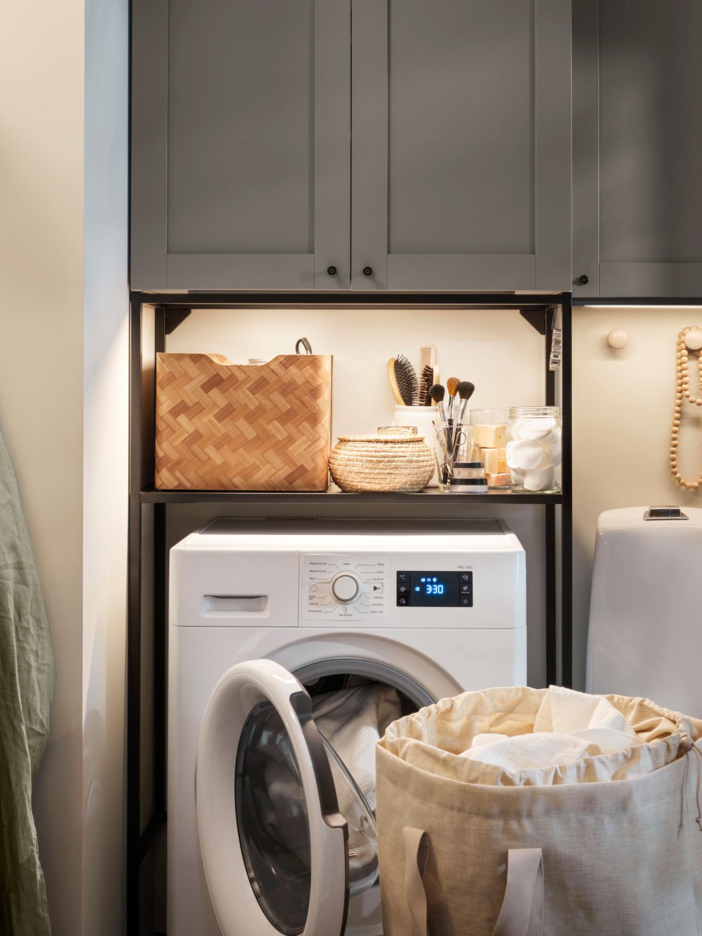 A bathroom laundry, storage with ENHET fronts in grey, an UDDARP washer/dryer combination and bathroom items on the shelf.