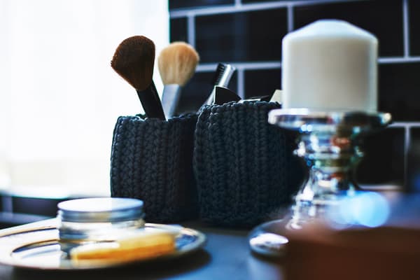 A bathroom make-up area with brushes in a woven basket.