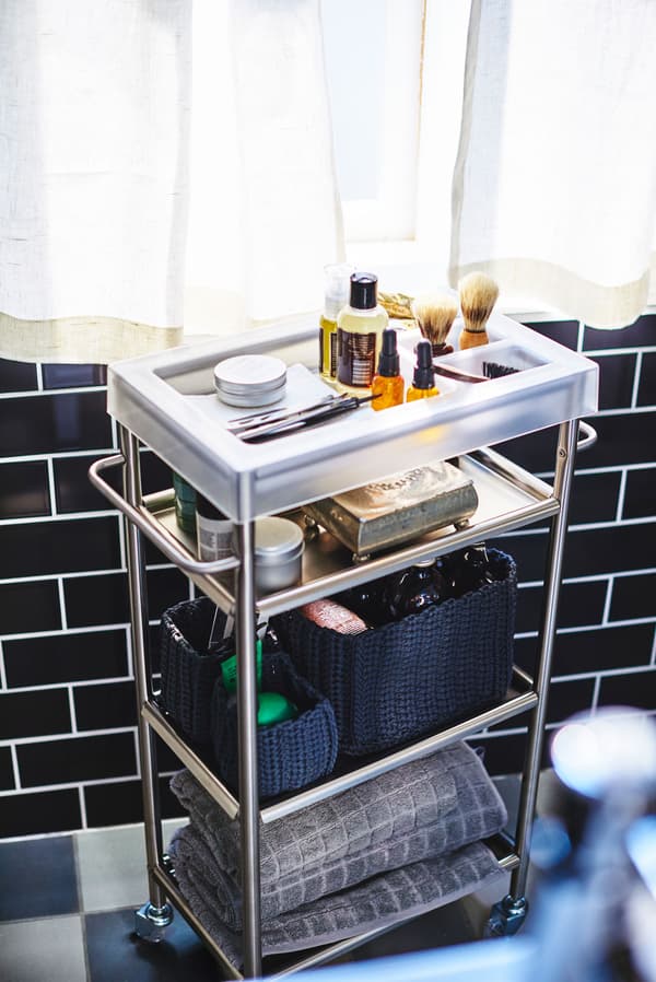 A bathroom trolley propped with mens grooming products, like shaving equipment and towels.