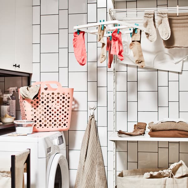 A bathroom with a washing machine, a storage combination for laundry with a cabinet, plus a laundry combination with a shelf.