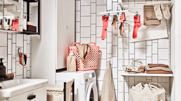 A bathroom with a washing machine, a storage combination for laundry with a cabinet, plus a laundry combination with a shelf.