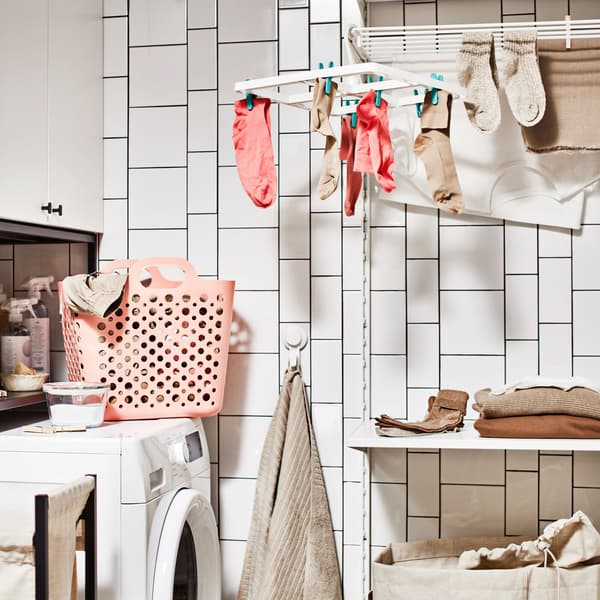 A bathroom with a washing machine, a storage combination for laundry with a cabinet, plus a laundry combination with a shelf.