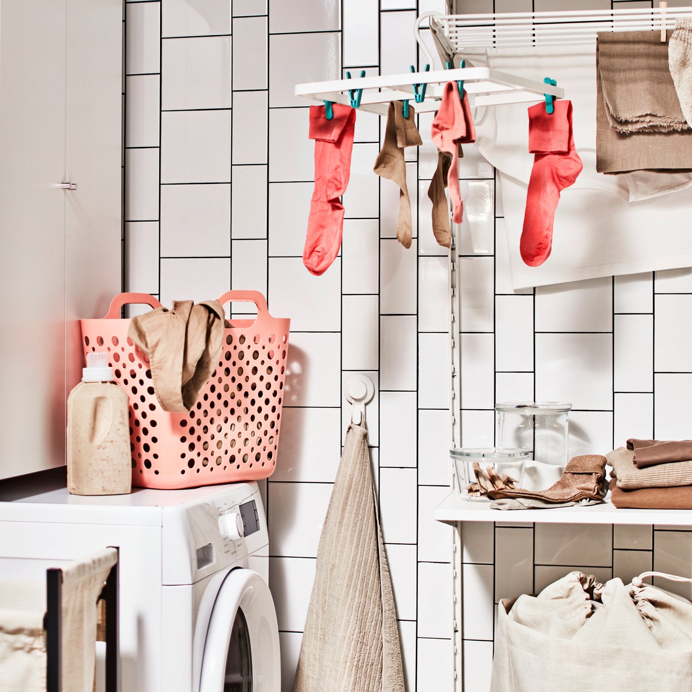 A bathroom with a washing machine, a storage combination for laundry with a cabinet, plus a laundry combination with a shelf.
