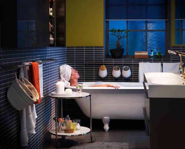 A bathroom with a woman relaxing in a roll top bath.