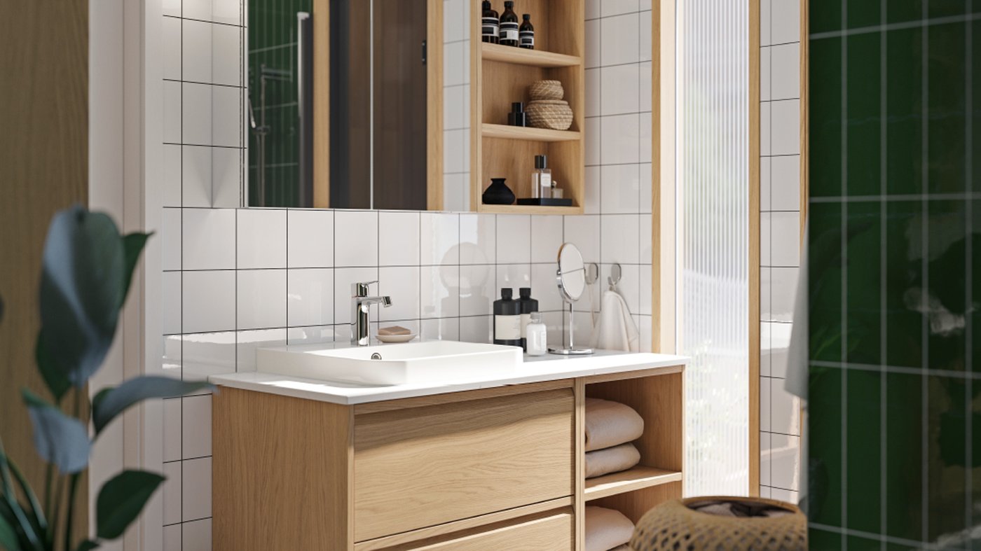 A bathroom with ÄNGSJÖN fronts in oak effect has a washstand with open and closed storage and a mirror cabinet above it.