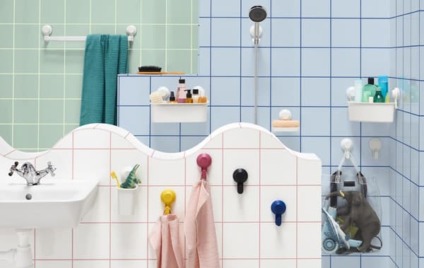A bathroom with wall-mounted towel rail, shower head holder, hooks, and boxes.