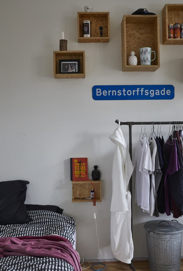 A bed, clothes rail, and open storage.