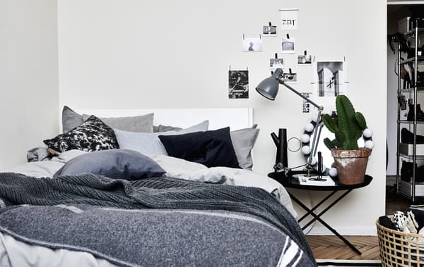 A bed covered in layers of throws and cushions.