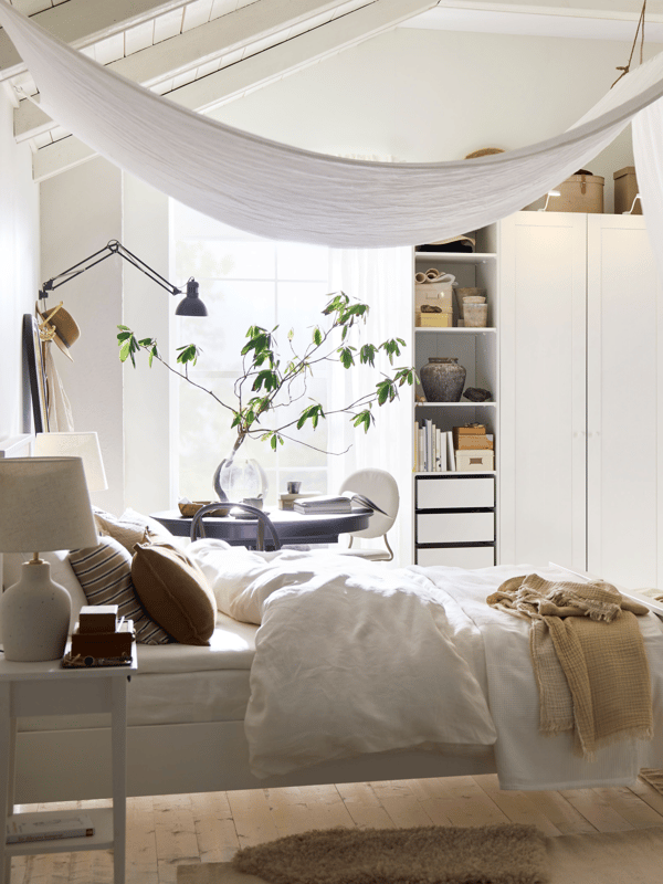 A bed covered in STRANDLUMMER bed linen and a green bedspread in front of a PAX/GULLABERG wardrobe in a dimly let bedroom.
