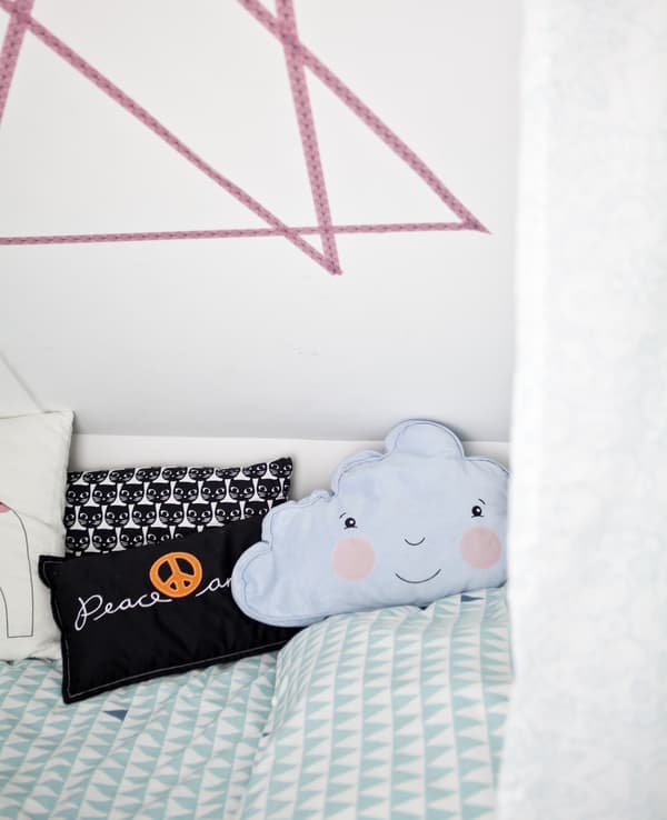 A bed decorated with colourful cushions.