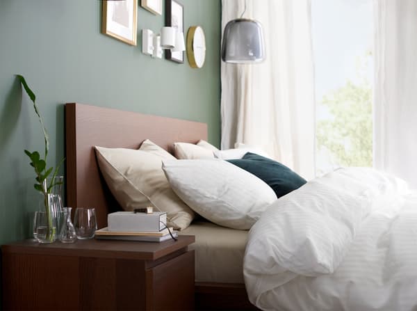 A bed frame and bedside table in brown stained ash veneer and a quilt cover, pillowcases and curtains in white.