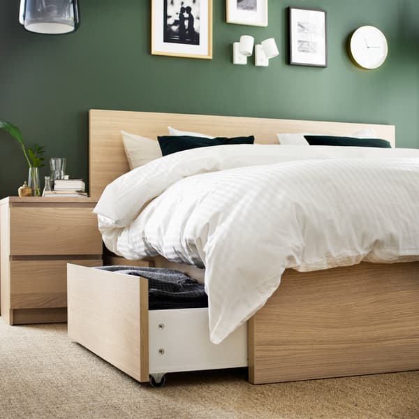 A bed frame and bedside table in white stained oak veneer and quilt cover and pillowcases in white.