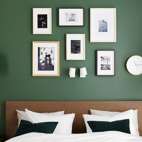 A bed frame in brown stained ash veneer,  quilt cover and pillowcases in white and gold-coloured frames.