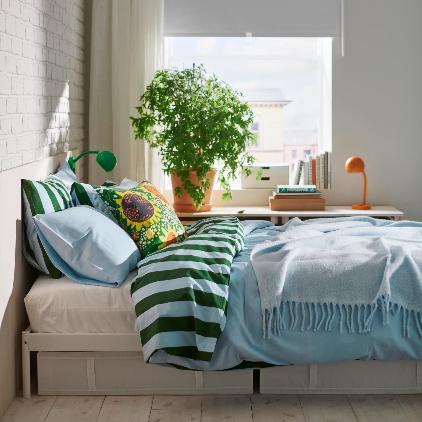 A bed with a plant on the background.