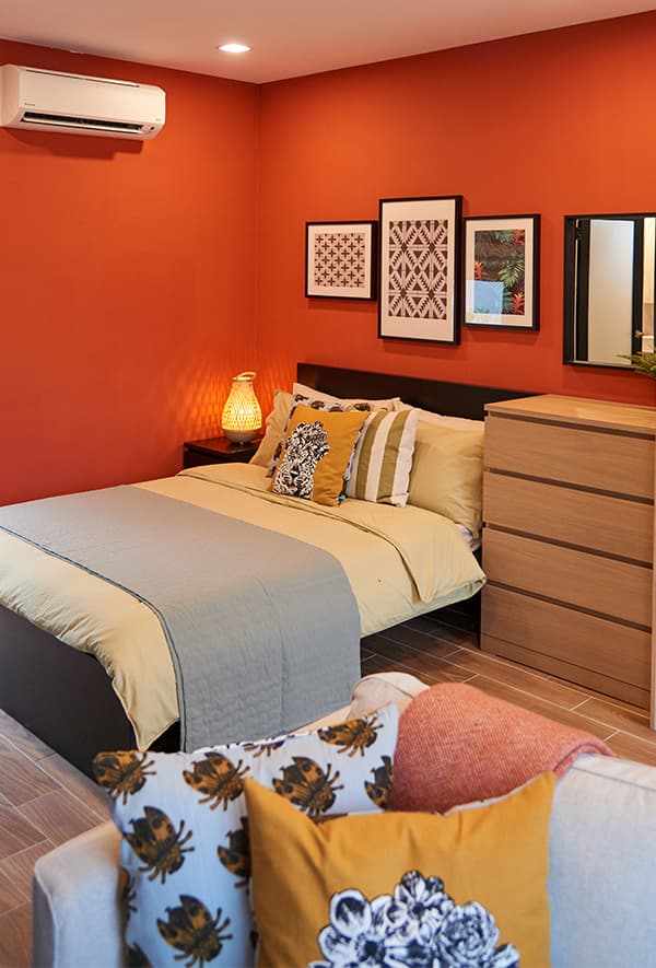 A bed with a wooden chest of drawer in a red room.