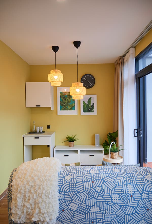 A bed with decorative blue and white bedsheet in a yellow room.