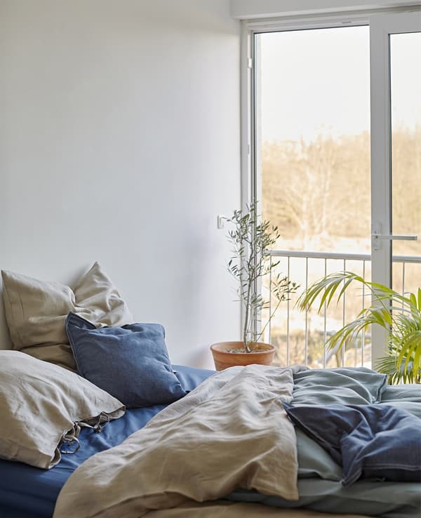 A bed with layered bedding in natural colours.