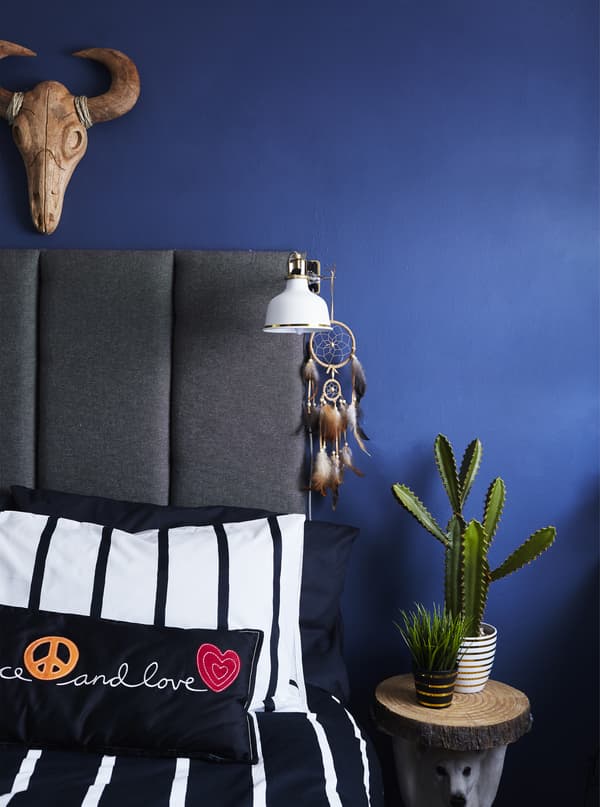 A bed with monochrome bedding and grey headboard.