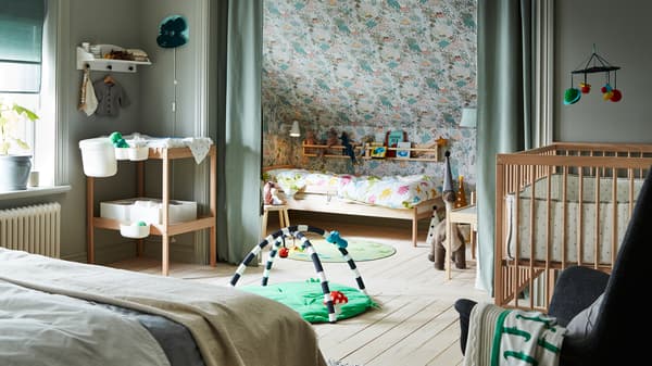 A bedroom containing a double bed, SNIGLAR cot, changing table and child’s bed with rail, and curtains dividing the space.