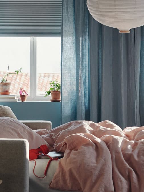 A bedroom interior with TRIPPEVALS block-out cellular blind shown half opened.