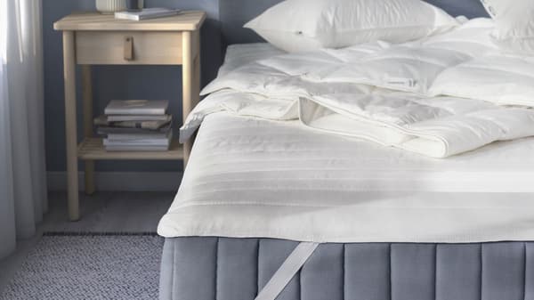 A bedroom set with mattress, nightstand and blue walls.