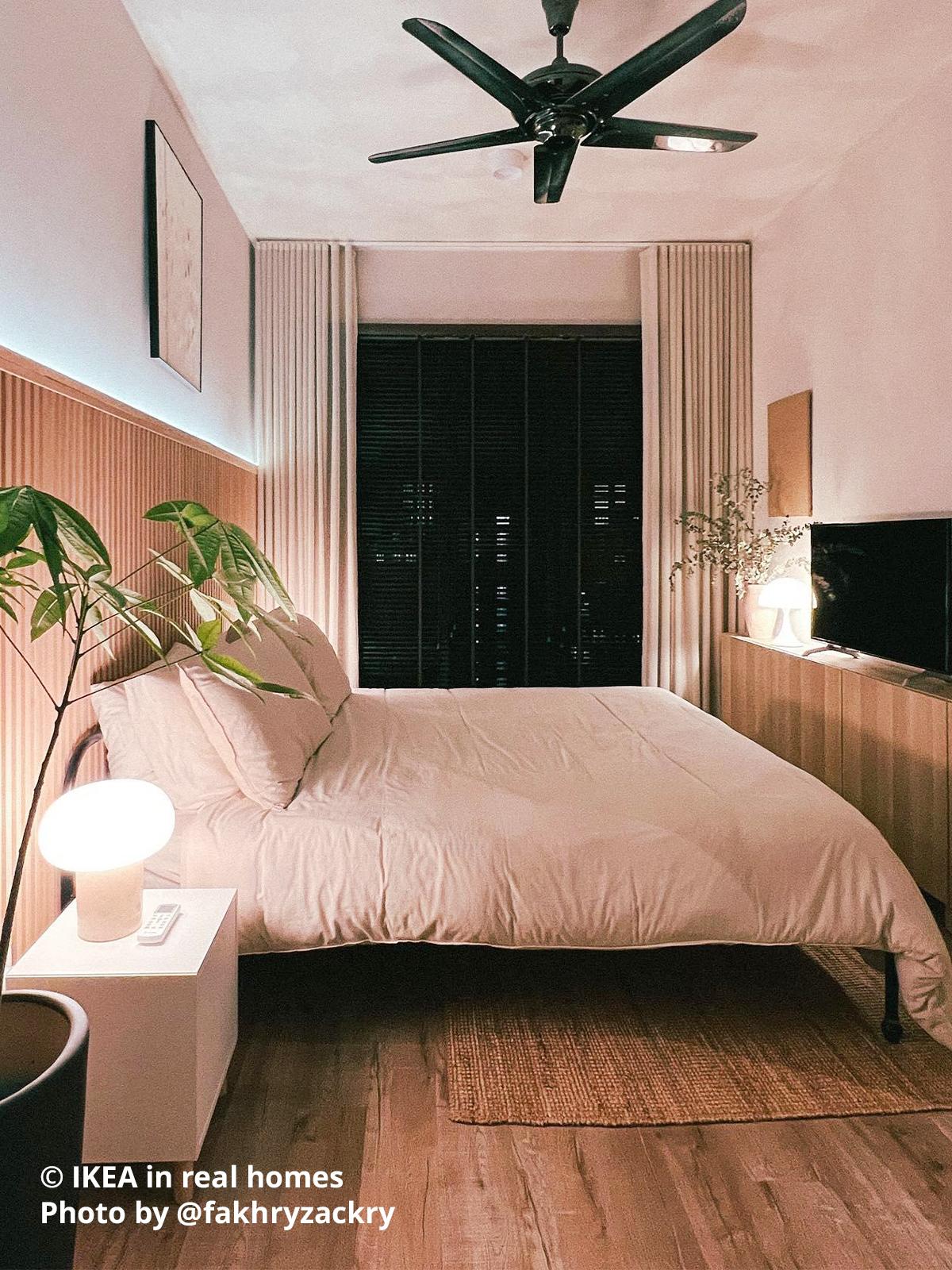 A bedroom setting - a glass opal white TOKABO table lamp is placed on top of the white EKET cabinet with wooden legs as bedside table next to a bed that resembles NESTTUN and a white stained oak effect BESTÅ storage combination with doors. Photo by instagrammer @fakhryzackry from IKEA in real homes ©