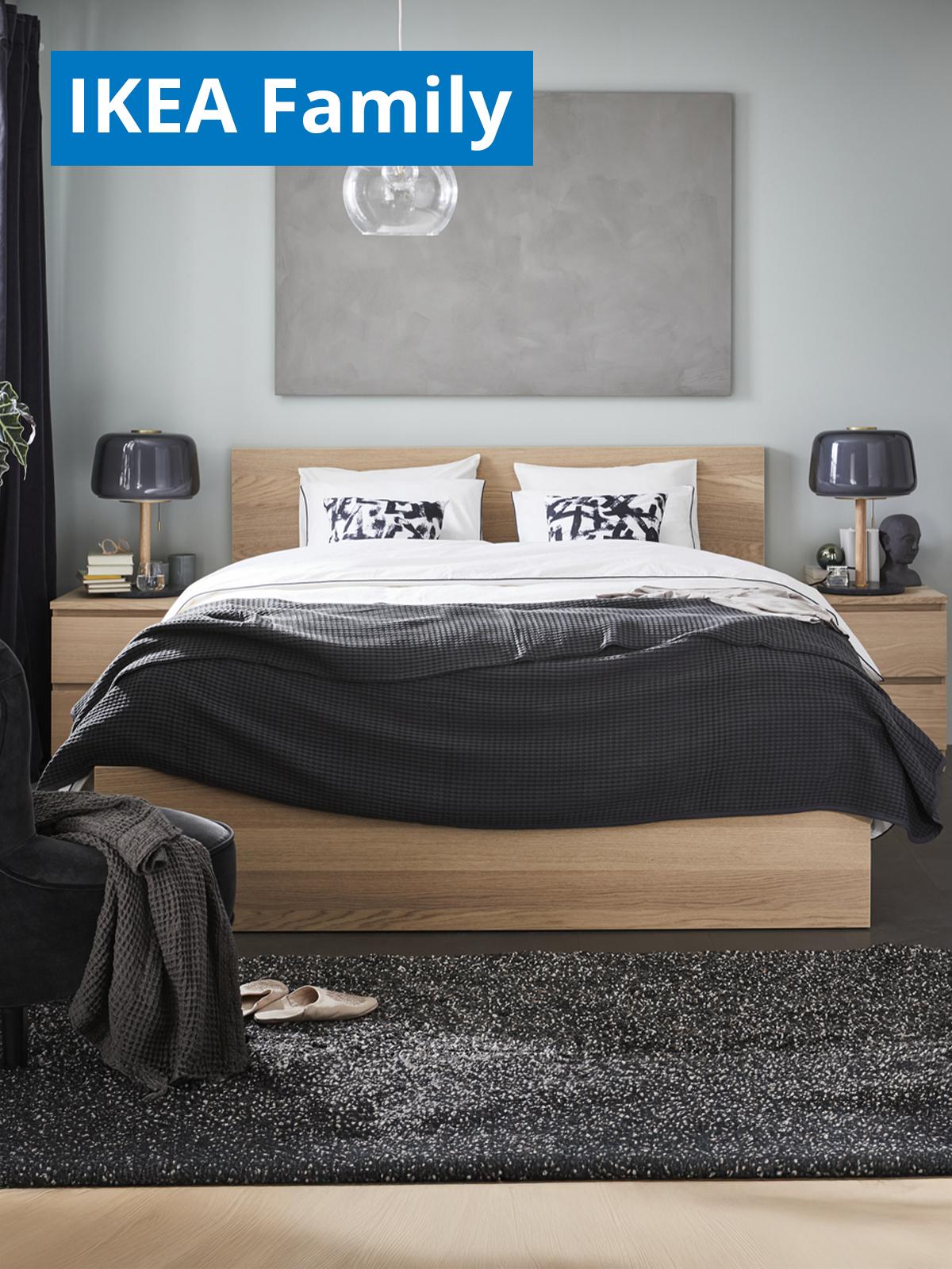 A bedroom setting featuring a white stained oak veneer MALM bed. On the top left corner, a blue tag with white text that reads "IKEA Family price".