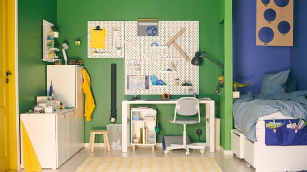 A bedroom with a dedicated study area complete with pegboard and cabinets for organization.