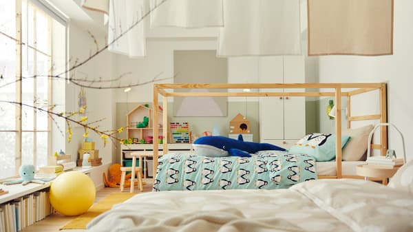 A bedroom with a KURA reversible bed and another bed parallel to each other opposite a wall with large windows.