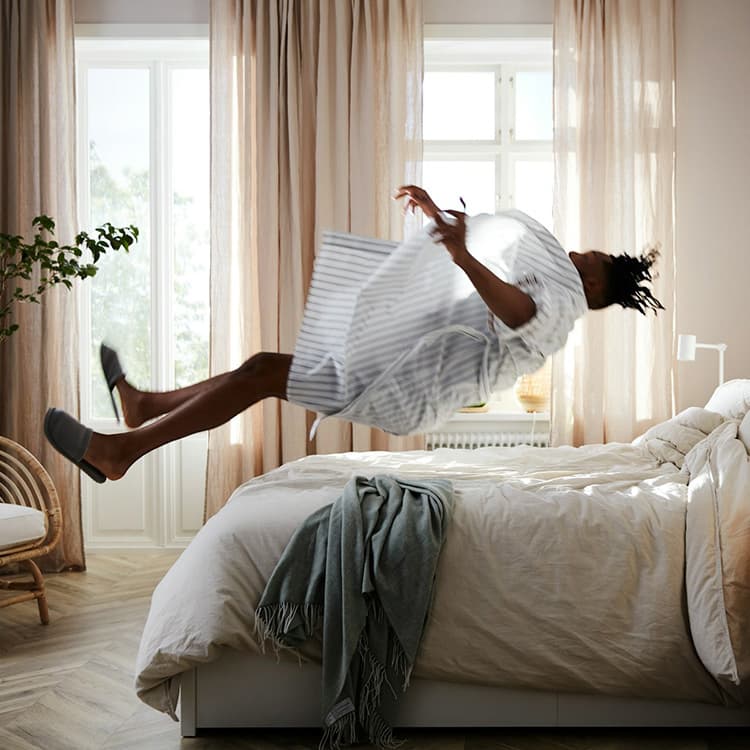 a bedroom with a person jumping onto a bed