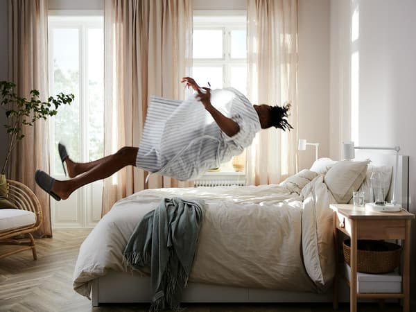 a bedroom with a person jumping onto a bed