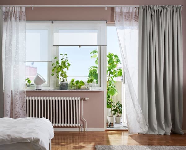 A bedroom with cosy white / grey curtains 