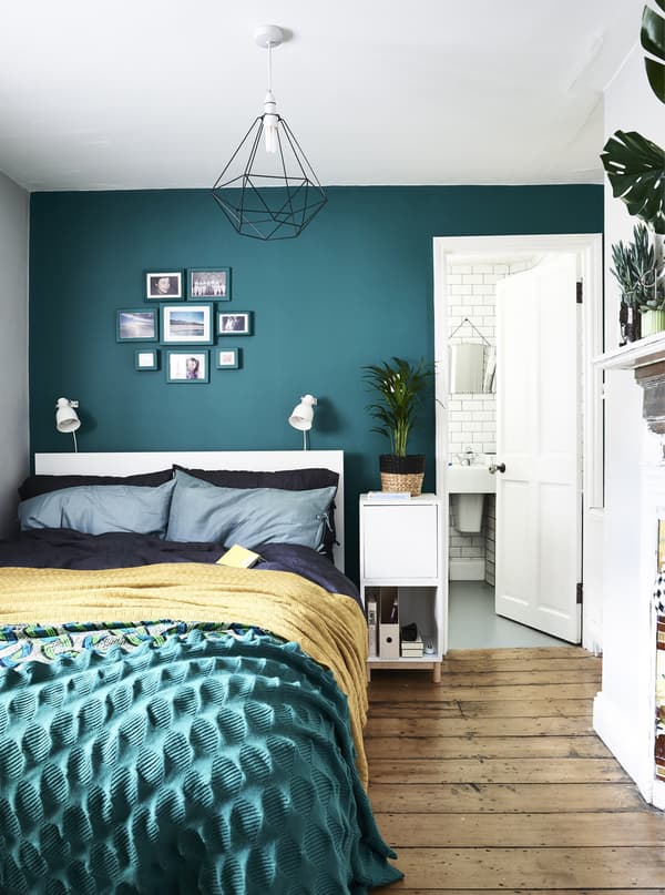 A bedroom with green wall and colourful bedding.