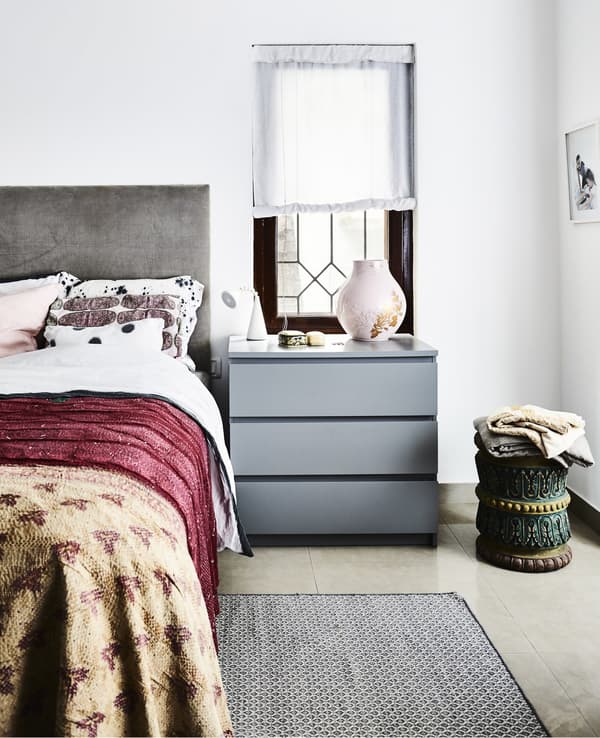 A bedroom with grey furniture and bright textiles.