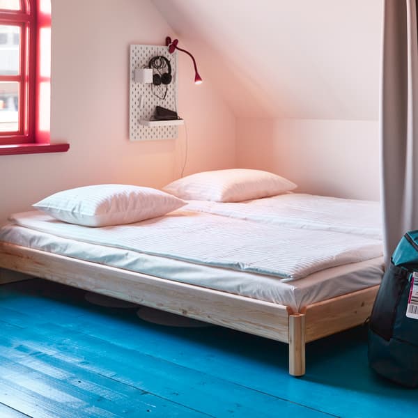 A bedroom with sloped ceiling and a small window showing two UTÅKER beds next to each other, white bedlinen on top.