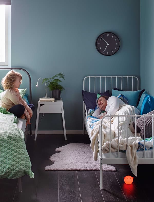 A bedroom with two beds and a parent and child.