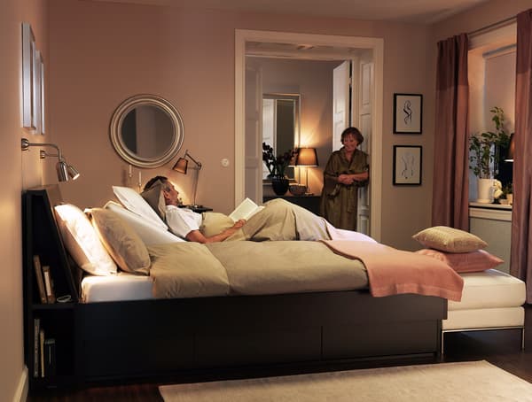 A bedroom with wooden bed frame, and neutral soft furnishings.