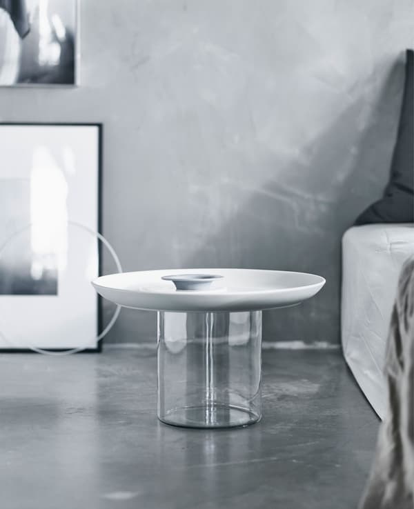 A bedside table in white next to a bed