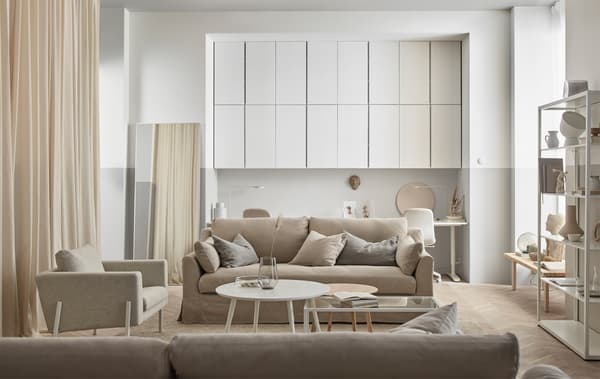 A beige and white living room with a wall of IVAR cabinets painted in similar tones as the room.