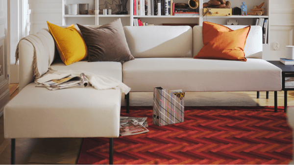 A beige LILLEHEM sofa in the living room with a red rug on the floor.