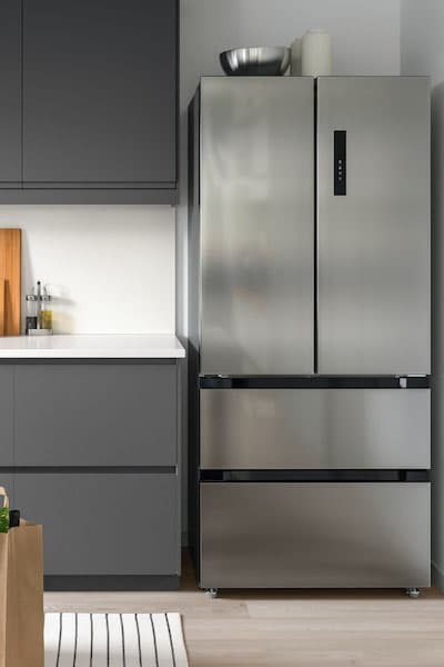 A big American fridge in stainless steel in a corner of a modern VOXTORP grey kitchen.
